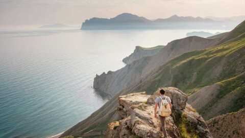 Young man travels alone on the backdrop of the mountains