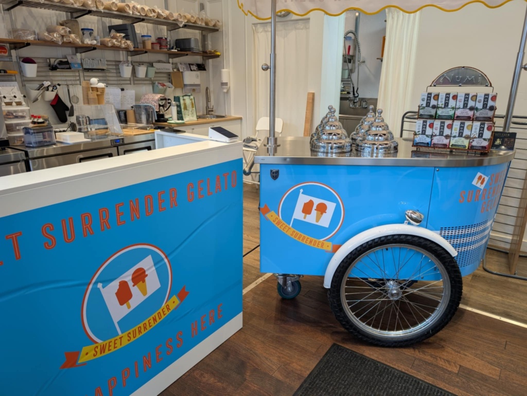 a blue and white gelato cart with a cart and a sign
